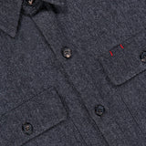 Close-up of the Cashmere Denim Effect Overshirt by ISAIA—a luxury men’s layering piece crafted in Italy, featuring a dark gray hue, button-up design, dual chest pockets, and subtle red stitching above the left pocket flap.