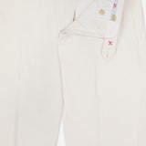 The ISAIA Cotton & Cashmere Comfort Trouser Pant features off-white fabric, a partially unbuttoned and unzipped front with visible button and hook closure, white waistband lining with red stitching, and adjustable side tabs for a tailored fit.