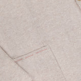 Close-up of ISAIA's Cotton Linen Jersey Sportcoat, made in Italy, showcasing its beige textured fabric, subtle red pocket stitching, and a single tan button near the lapel.