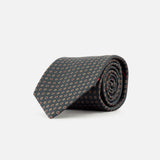 A rolled-up ISAIA Dot Pattern Tie in dark gray silk, featuring a small repeating red and white geometric motif, displayed on a plain white background.