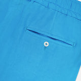 Close-up of the back pocket on ISAIA's Drawstring Wide Leg Linen Corallo Trouser Pant in bright blue, featuring an elastic waistband and button closure—ideal for effortless vacation style.
