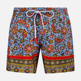 ISAIA's Drawstring Printed Swim Trunk features a vibrant floral and paisley print on light blue, white drawstring waistband, and multicolored bands at the hem—perfect for standout men's beach style.