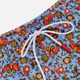 Close-up of ISAIA Drawstring Printed Swim Trunk with a blue base and colorful floral pattern in red, yellow, and brown; features a white drawstring waistband—perfect men’s swimwear for vibrant beach style.