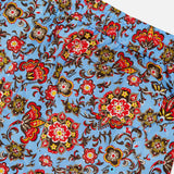 Close-up of ISAIA Drawstring Printed Swim Trunk: men's blue swimwear with a bold red, yellow, brown, and black floral print, elastic waistband, and back pocket.