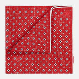 The ISAIA Floral Print Pocket Square, crafted in Italy, showcases a red silk design with a small white and blue floral pattern and displays both its stylish front and the white-edged reverse when folded.