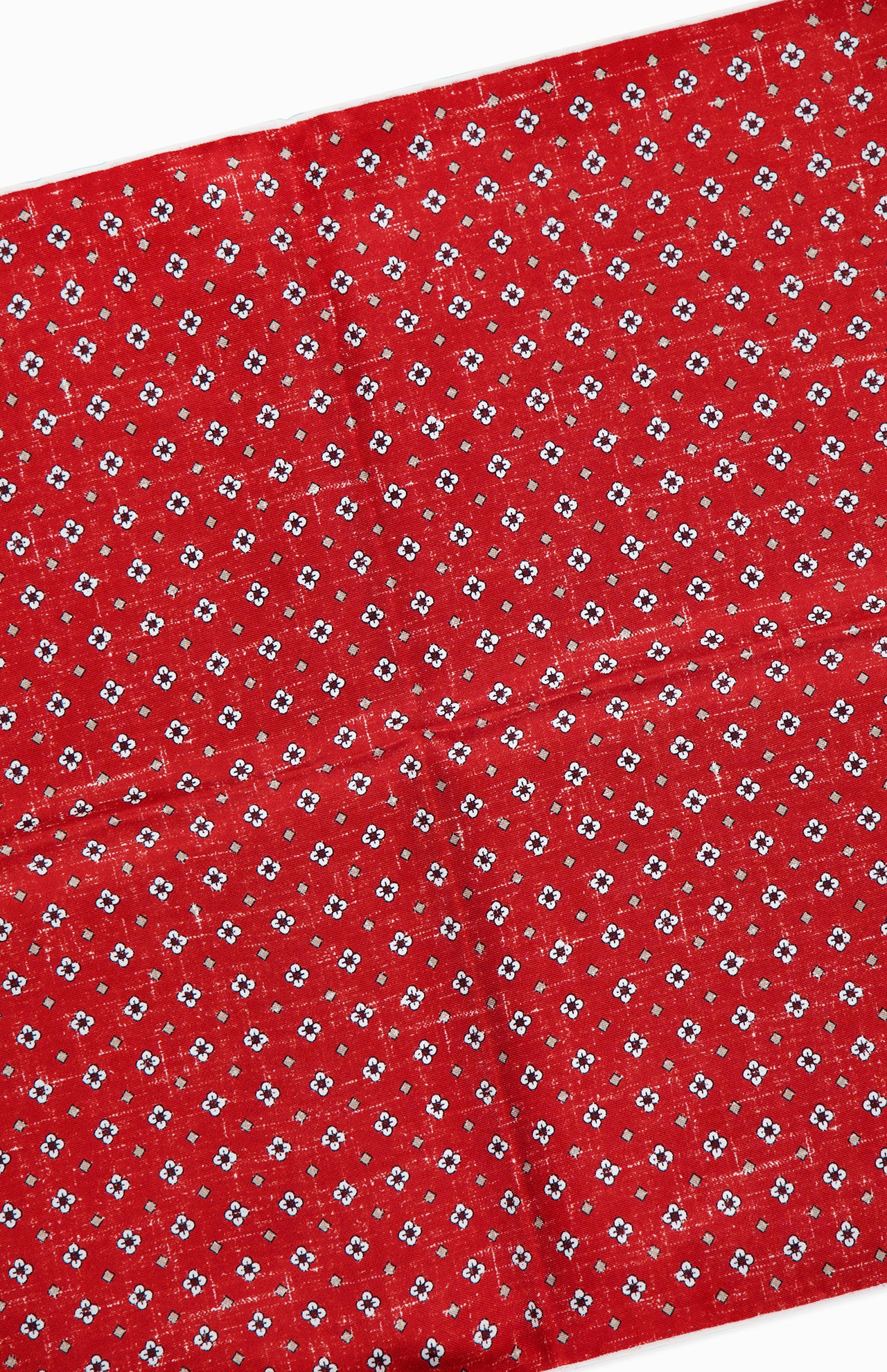 The ISAIA Floral Print Pocket Square is crafted in Italy from red silk and features a diagonal pattern of small white and black flowers. The surface has a subtly creased appearance.