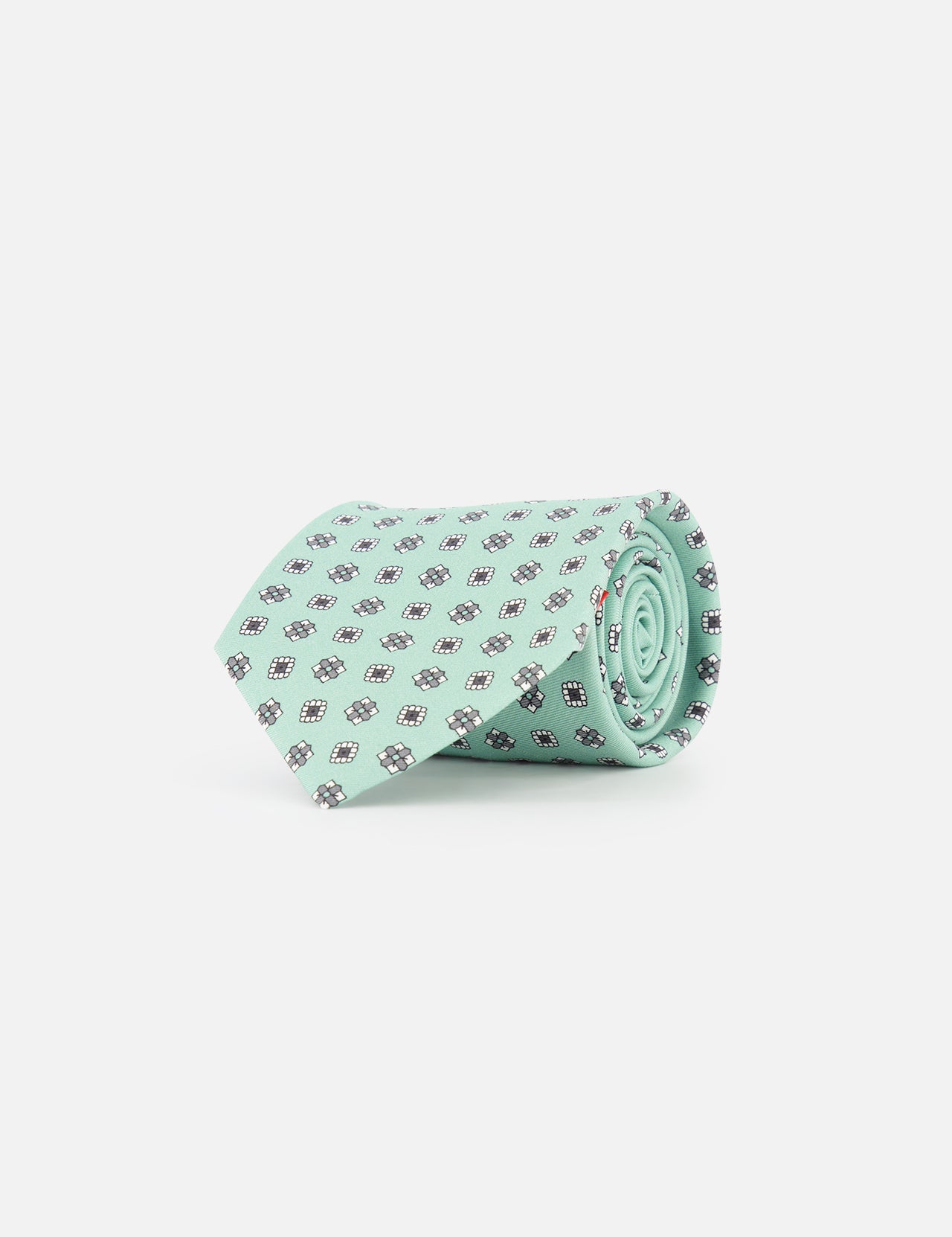 The ISAIA Geometric Floral Print Tie is a light green silk necktie with a pattern of small dark blue and white geometric floral designs, shown rolled on a plain white background.
