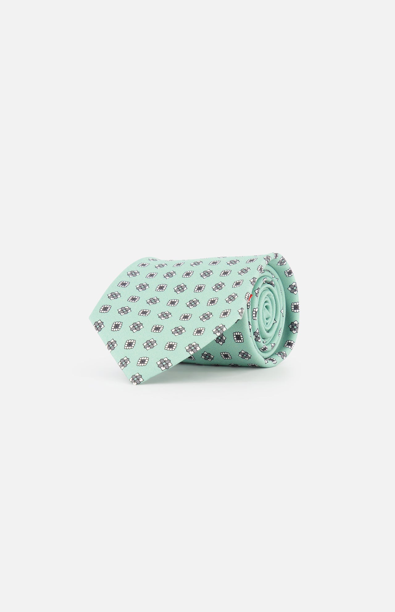 The ISAIA Geometric Floral Print Tie is a light green silk necktie with a pattern of small dark blue and white geometric floral designs, shown rolled on a plain white background.