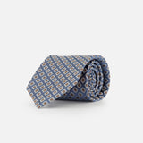 A rolled-up blue silk tie by ISAIA, featuring a floral print design, displayed on a plain white background.