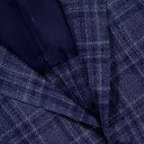 Close-up of the ISAIA Galles Over Check Rustic Sportcoat, made in Italy. This premium navy jacket features a textured blue plaid with intersecting white and light blue lines, single black button, and dark blue lining.