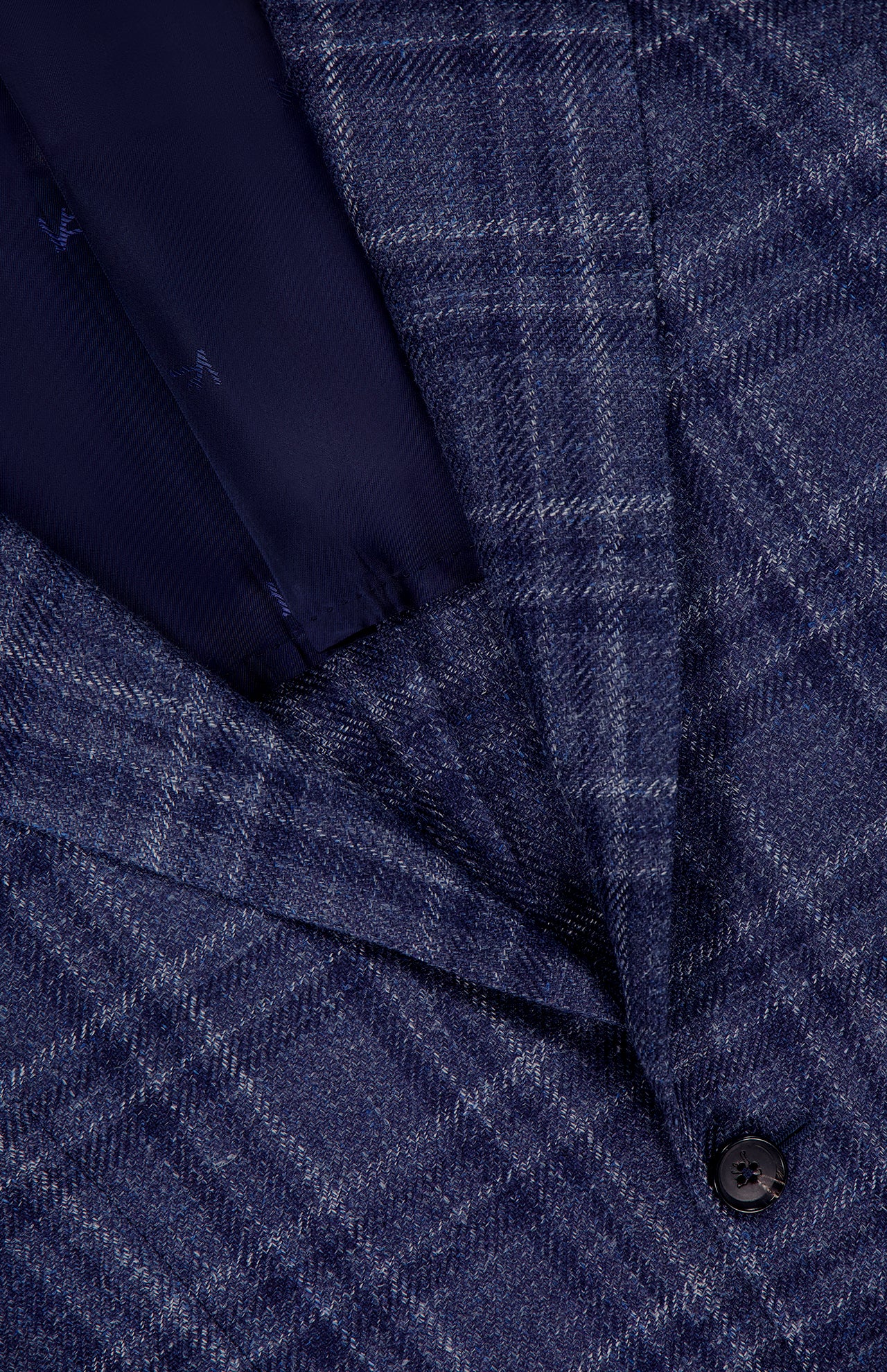 Close-up of the ISAIA Galles Over Check Rustic Sportcoat, made in Italy. This premium navy jacket features a textured blue plaid with intersecting white and light blue lines, single black button, and dark blue lining.
