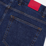 Close-up of the back pocket of ISAIA’s Napoli Stretch Denim Jeans in blue, highlighted with orange stitching and a red leather patch on the waistband bearing a subtle embossed logo. Crafted from a luxurious cotton-cashmere blend, these jeans feature a tapered leg for a modern, streamlined fit.