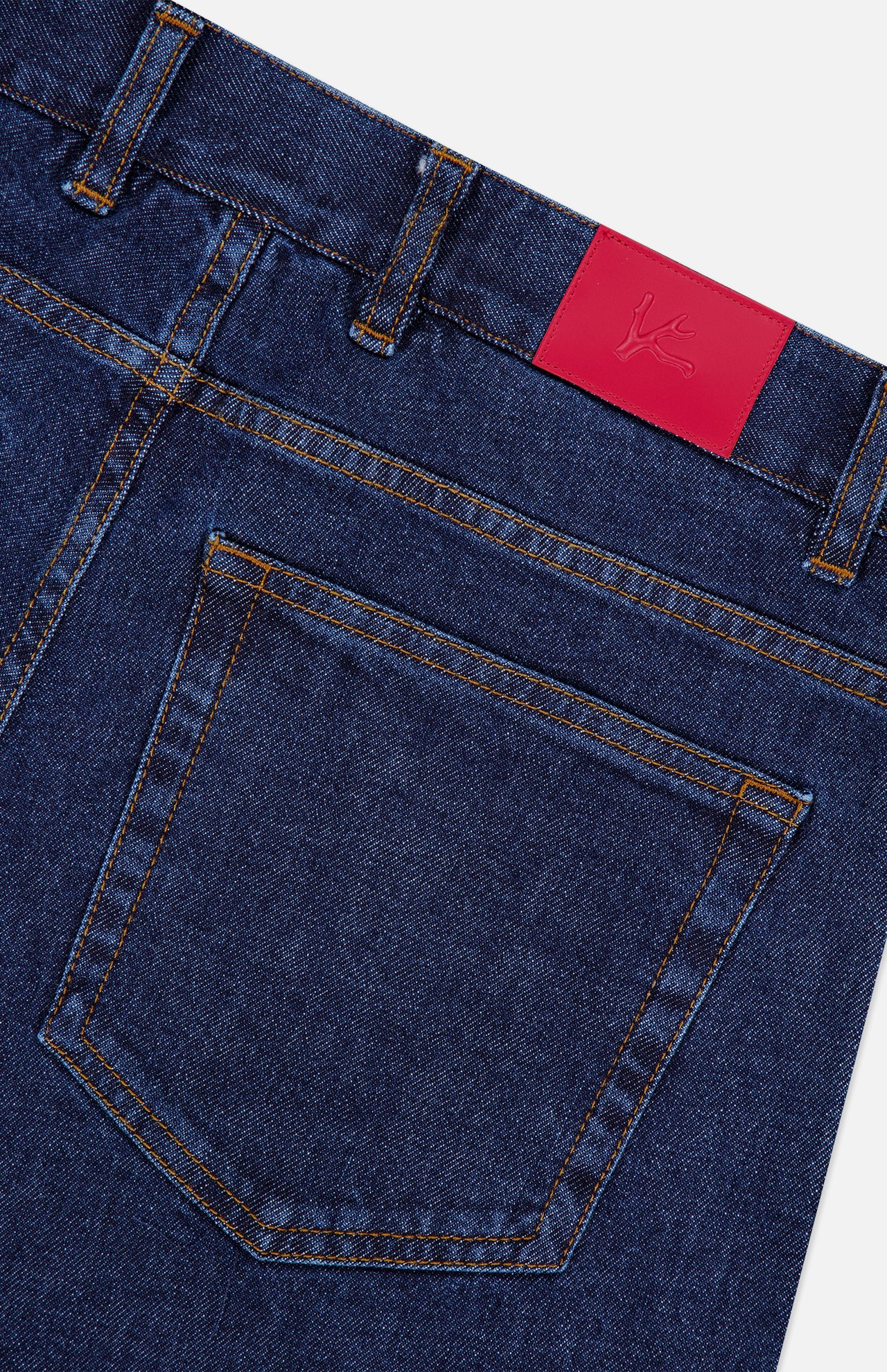 Close-up of the back pocket of ISAIA’s Napoli Stretch Denim Jeans in blue, highlighted with orange stitching and a red leather patch on the waistband bearing a subtle embossed logo. Crafted from a luxurious cotton-cashmere blend, these jeans feature a tapered leg for a modern, streamlined fit.