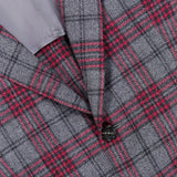 Close-up of an Over Checkered Cashwool Sportcoat by ISAIA in grey and maroon plaid, highlighting two black buttons and a glimpse of the light grey inner lining. This Italian-made wool cashmere jacket features sophisticated red and black overcheck stripes for a refined touch.