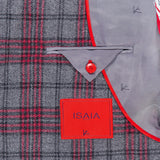Close-up of the Over Checkered Cashwool Sportcoat by ISAIA, an Italian-made jacket in a grey and maroon plaid pattern. It features a red-bordered pocket, signature red button, and a distinctive red rectangular ISAIA label. The light gray lining is adorned with finely embroidered fish motifs, showcasing the meticulous craftsmanship of this wool-cashmere sportcoat.