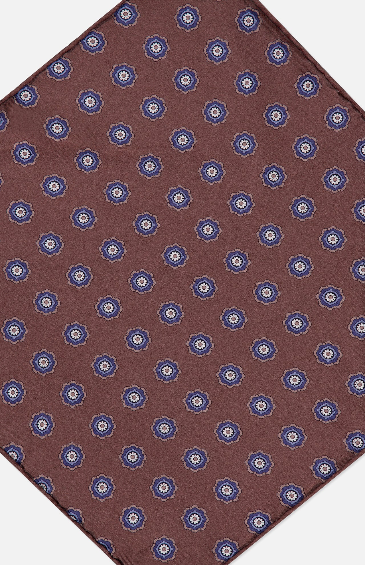 The Paisley Pocket Square by ISAIA is crafted in Italy from brown silk and features a repeating pattern of small blue and white floral motifs arranged diagonally on a white background.