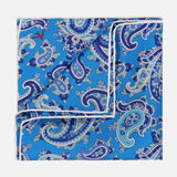 The ISAIA Paisley Print Pocket Square is a blue silk accessory with a white border and an intricate paisley pattern in blue, white, and purple shades. Made in Italy.