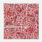 The ISAIA Paisley Print Pocket Square is crafted from silk and showcases a red, white, and brown paisley pattern with a crisp white border, elegantly displayed against a white background.