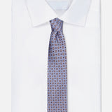 A neatly folded white dress shirt with a pointed collar, paired with ISAIA’s Pattern Neck Tie—an exquisitely made-in-Italy silk accessory in light blue, featuring a small geometric square design on a white background.