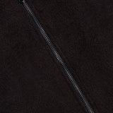 Close-up of a black fuzzy fabric with a central silver zipper, showcasing the luxurious texture of the ISAIA Peruvian Alpaca Varsity Bomber Jacket. A small section of red fabric appears near the top left corner beside the zipper, emphasizing the distinctive detailing characteristic of this premium men’s outerwear.