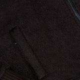 Close-up of the Peruvian Alpaca Varsity Bomber Jacket by ISAIA in dark brown, featuring a textured finish, visible side pocket, partial zipper detail, and ribbed hem and cuffs—an elevated reinterpretation of classic men’s outerwear.