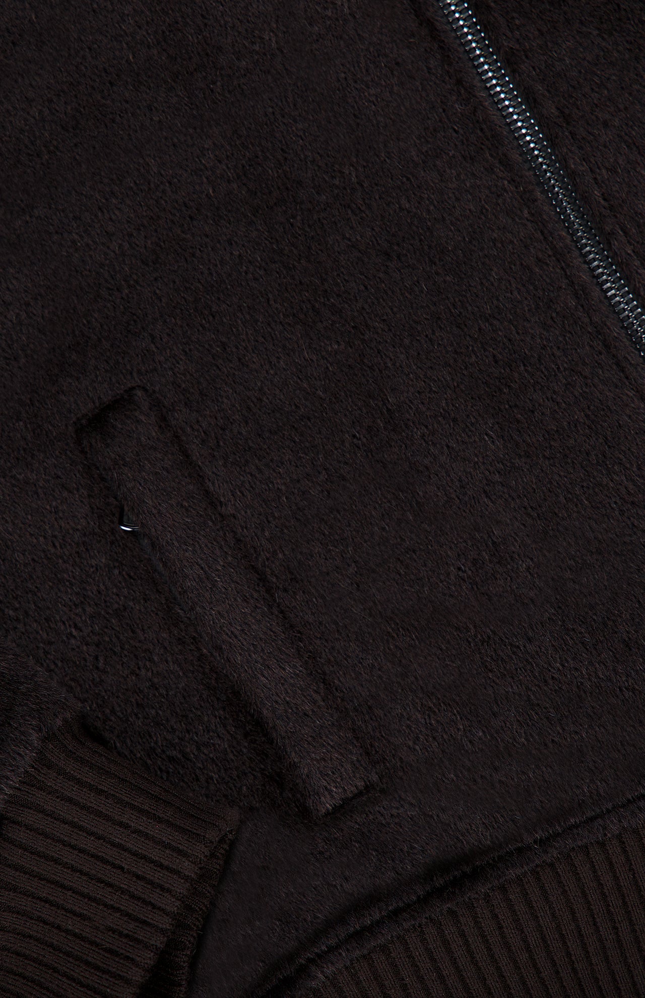 Close-up of the Peruvian Alpaca Varsity Bomber Jacket by ISAIA in dark brown, featuring a textured finish, visible side pocket, partial zipper detail, and ribbed hem and cuffs—an elevated reinterpretation of classic men’s outerwear.