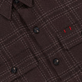Close-up of the ISAIA Plaid Knit Effect Overshirt, featuring a luxurious brown plaid knit-effect design, black buttons, a chest pocket with two small vertical red stitches above it, crafted in a refined cashmere overshirt style.