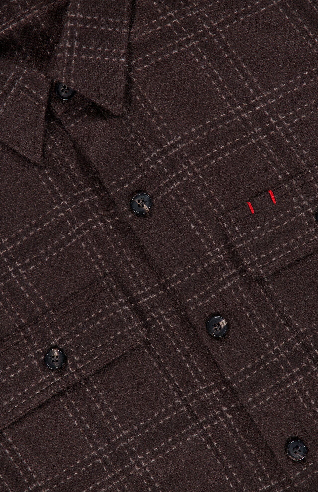 Close-up of the ISAIA Plaid Knit Effect Overshirt, featuring a luxurious brown plaid knit-effect design, black buttons, a chest pocket with two small vertical red stitches above it, crafted in a refined cashmere overshirt style.
