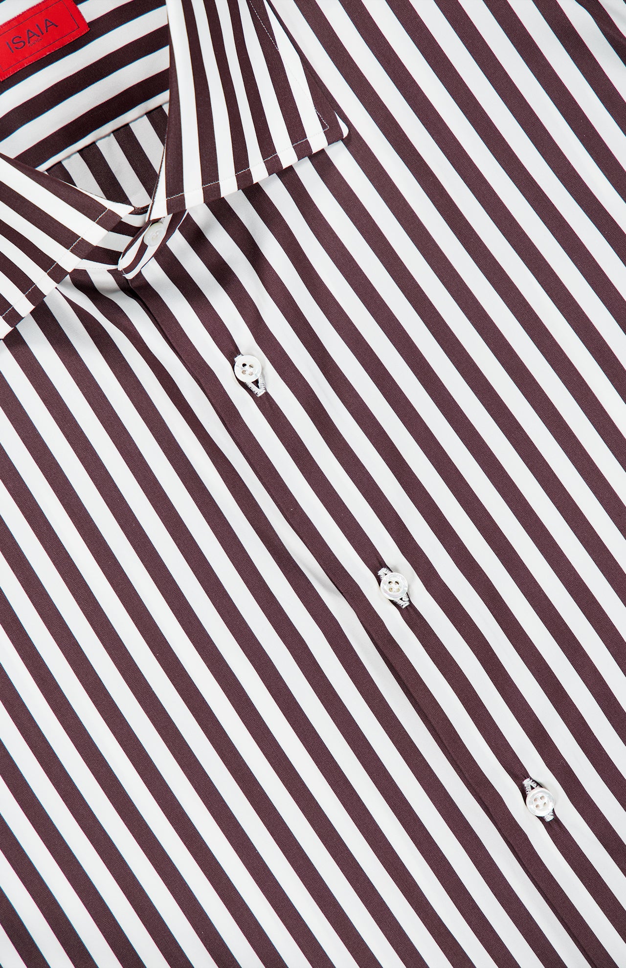 Close-up of the Rigato Popeline Dress Shirt by ISAIA, an Italian design featuring vertical black and white stripes. Crafted from easy-care cotton, the shirt showcases white buttons and a pointed collar, with part of a signature red label visible at the top left.