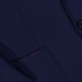 Close-up of the ISAIA Scuba Wool Comfort Suit Jacket in dark navy blue, featuring two black buttons and a front pocket with distinctive red stitching detail near the top edge.