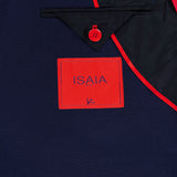 Close-up of the Scuba Wool Comfort Suit Jacket by ISAIA, highlighting its navy lining with red trim, a distinctive red button, and a rectangular red label featuring the blue ISAIA logo—showcasing the refined Italian craftsmanship of this sportcoat.