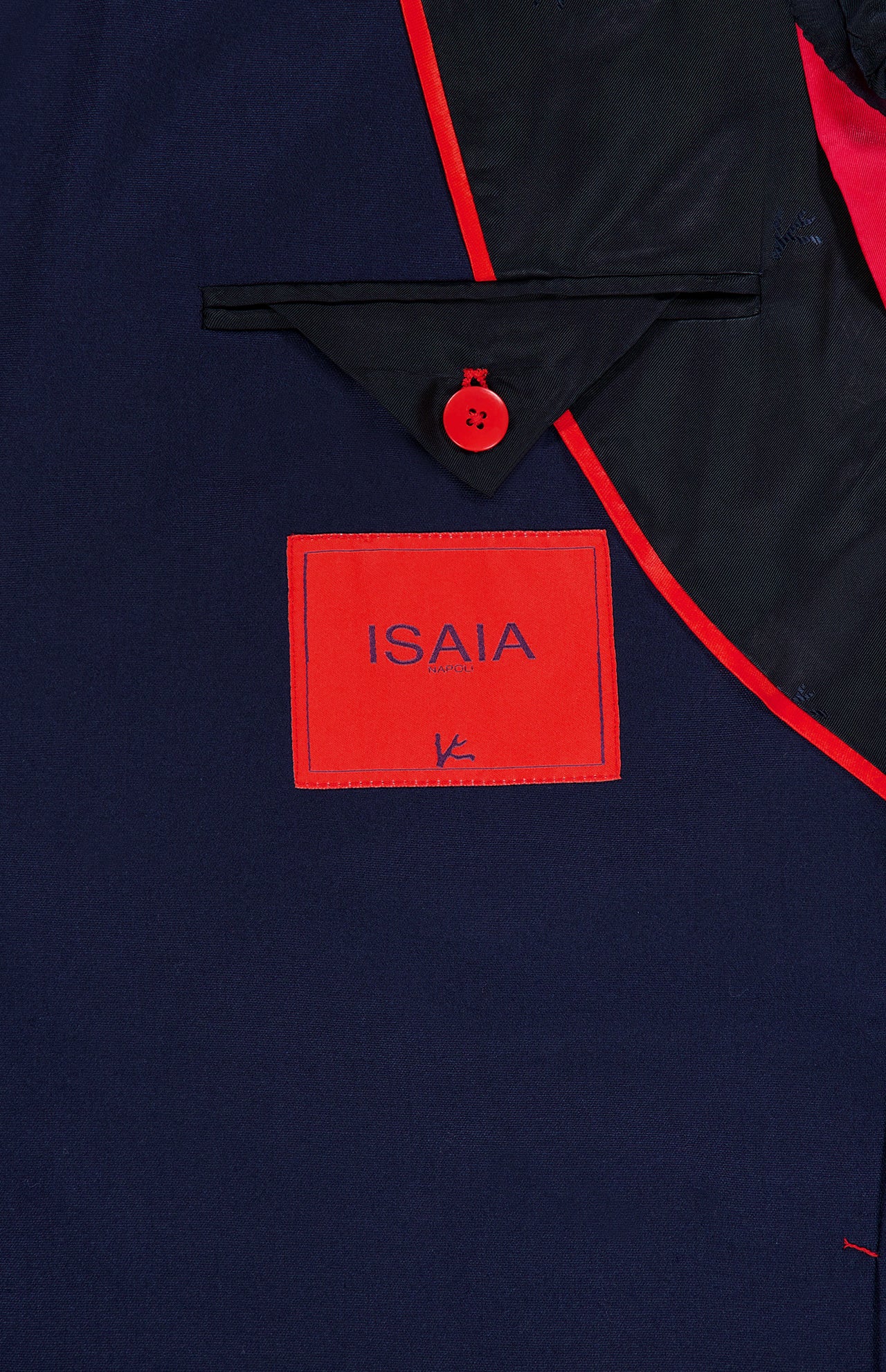 Close-up of the Scuba Wool Comfort Suit Jacket by ISAIA, highlighting its navy lining with red trim, a distinctive red button, and a rectangular red label featuring the blue ISAIA logo—showcasing the refined Italian craftsmanship of this sportcoat.