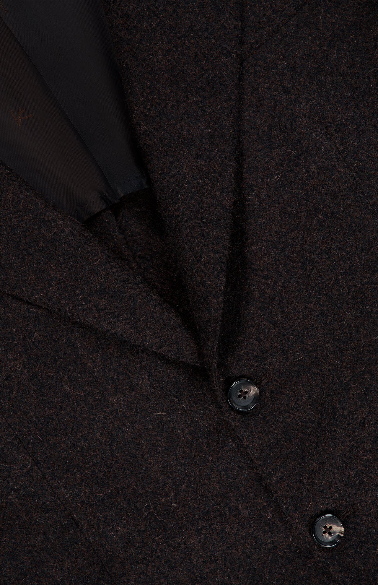 Close-up of the ISAIA Soft Boucle Alpaca & Wool Sportcoat, crafted in Italy in a rich dark brown hue, featuring two black buttons and a portion of the lapel with a glimpse of the black inner lining.