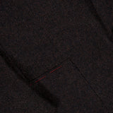 Close-up of the ISAIA Soft Boucle Alpaca & Wool Sportcoat, made in Italy. This dark brown jacket features a black button, lapel, and pocket accented with two short red stitches. The fabric is an alpaca wool blend with a textured boucle appearance.