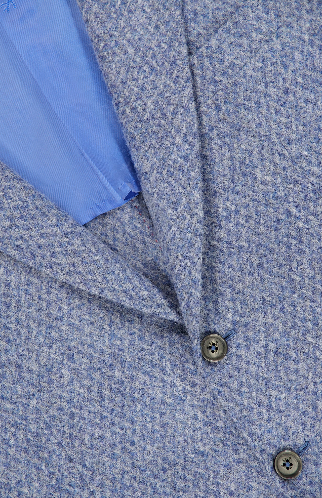 Close-up of the ISAIA Soft Boucle Alpaca & Wool Sportcoat, crafted in Italy in a textured light blue fabric, featuring two dark buttons and a glimpse of its smooth, light blue inner lining.
