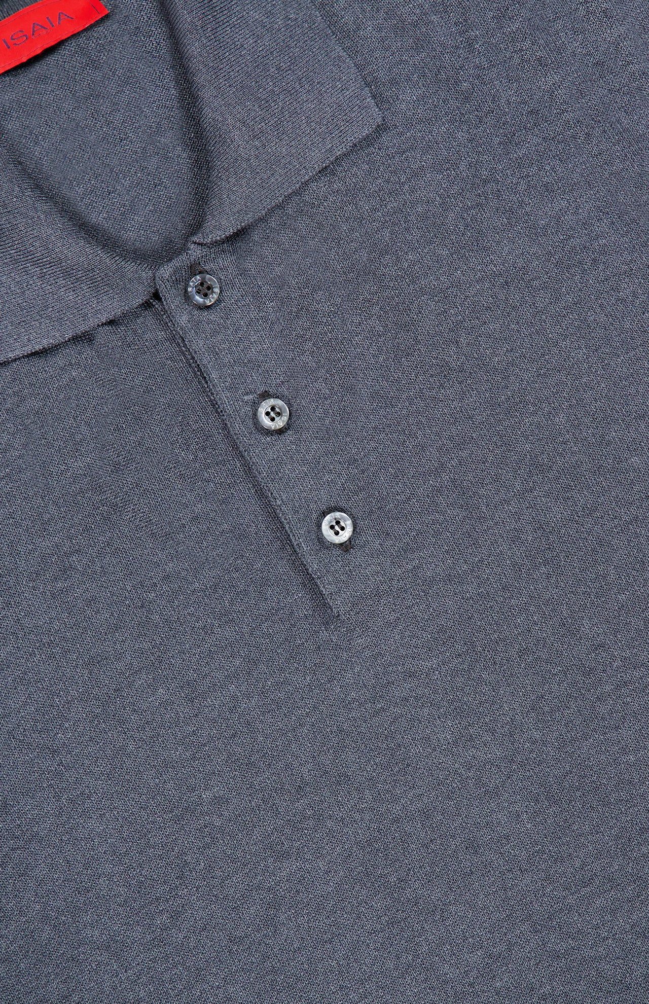 Close-up of the ISAIA Solid Silk Long Sleeve Polo Shirt in luxury grey, featuring a three-button placket and a classic collar, lying flat. A small part of a red tag is visible at the top left corner.