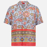 The ISAIA Superlino Print Linen Floral Camp Shirt features a light blue base with red, yellow, and brown floral and paisley designs plus a multicolored geometric border at the hem, creating a stylish vacation-ready look.