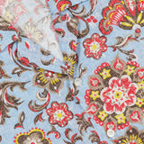 Close-up of the ISAIA Superlino Print Linen Floral Camp Shirt in blue, featuring a multicolor paisley pattern, white buttons partially unfastened, and a visible red brand tag inside the collar.