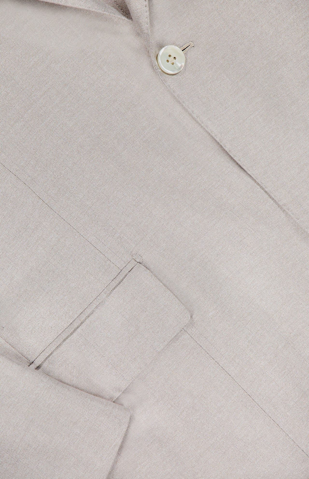 Close-up of ISAIA's Unito Soft Silk Sportcoat in light beige, made in Italy. Features include a single-breasted design, welt pocket with flap, single white button, visible silk texture, and precise stitching.