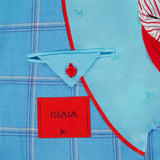 Close-up of ISAIA’s Over Check Top Cashsilk Sportcoat: blue plaid cashmere-silk lining with red piping, a red button on a triangular flap, ISAIA red fabric label, and a section of red-white striped fabric—crafted in Italy.
