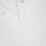 Close-up of the ISAIA Seersucker Short Sleeve Camp Shirt featuring a textured white finish, spread collar, and three white buttons. A red ISAIA tag is partially visible at the top left.