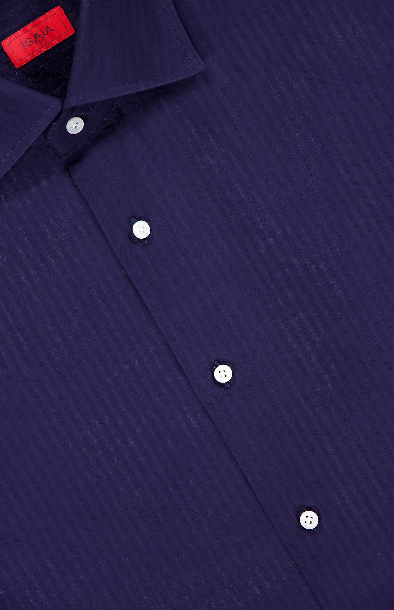 Close-up of the ISAIA Seersucker Long Sleeve Shirt in navy, featuring white buttons and a red ISAIA label inside the collar.
