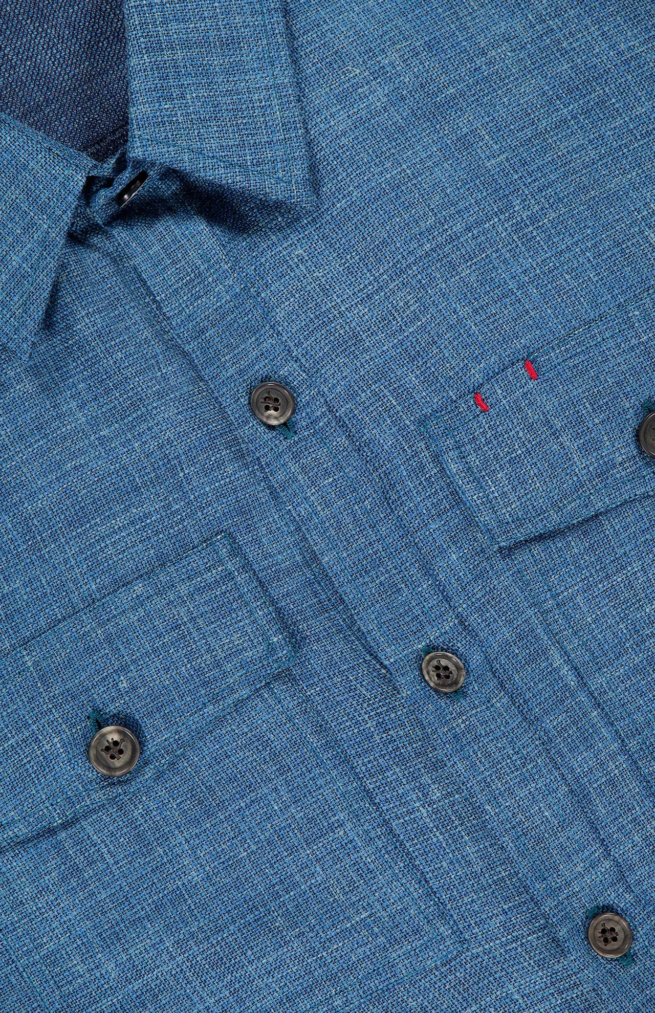 Close-up of the ISAIA Tela Mat Effect Overshirt featuring textured blue fabric, dark buttons, two chest pockets, a collar, and two small red stitches above the left pocket.