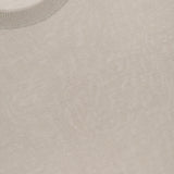 Close-up of an ISAIA Wool Cashsilk T-Shirt in light beige, featuring a ribbed crew neckline and crafted from luxurious wool, silk, and cashmere. A red ISAIA label is partially visible at the top left. Made in Italy.