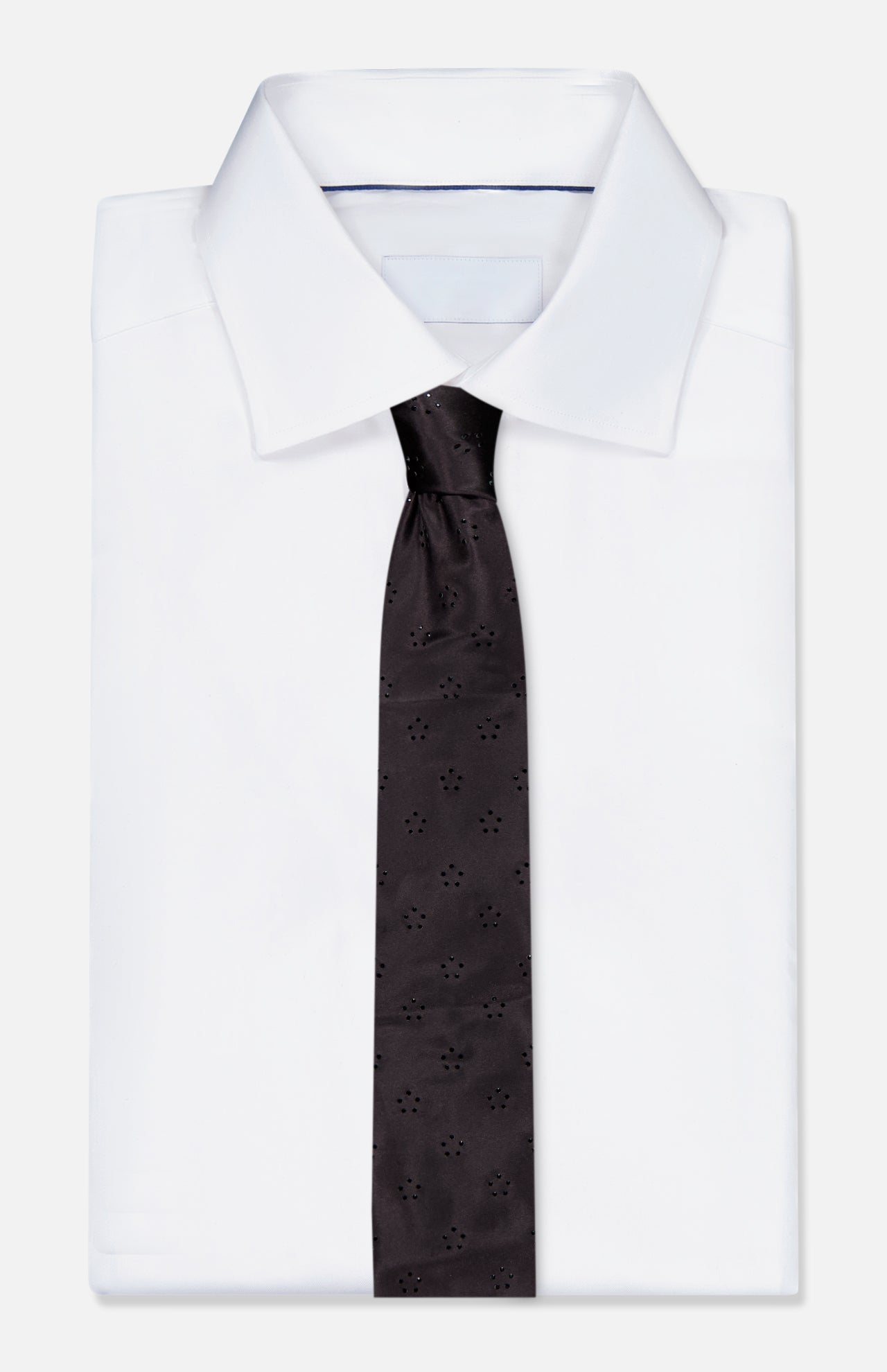 A folded white dress shirt with a stiff collar, paired with the ITALO FERRETTI Tonal Jeweled Neck Tie, which features a subtle dot and floral pattern, displayed on a plain light background.