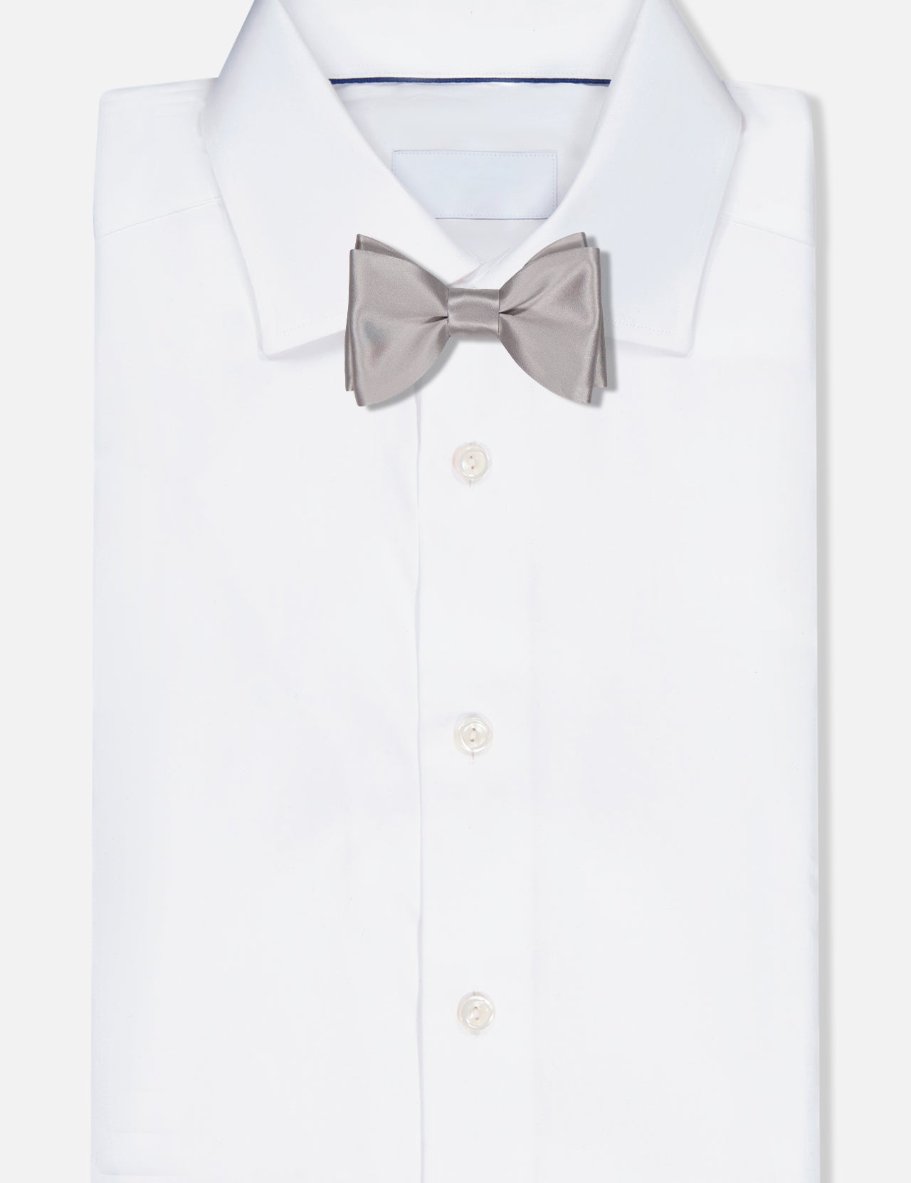 A neatly folded white dress shirt with an ITALO FERRETTI Satin Bowtie in light grey, handmade in Italy, displayed on a plain white background.