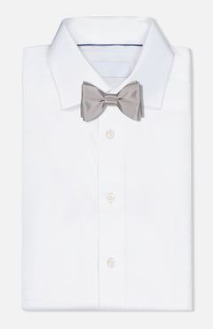 A neatly folded white dress shirt with an ITALO FERRETTI Satin Bowtie in light grey, handmade in Italy, displayed on a plain white background.