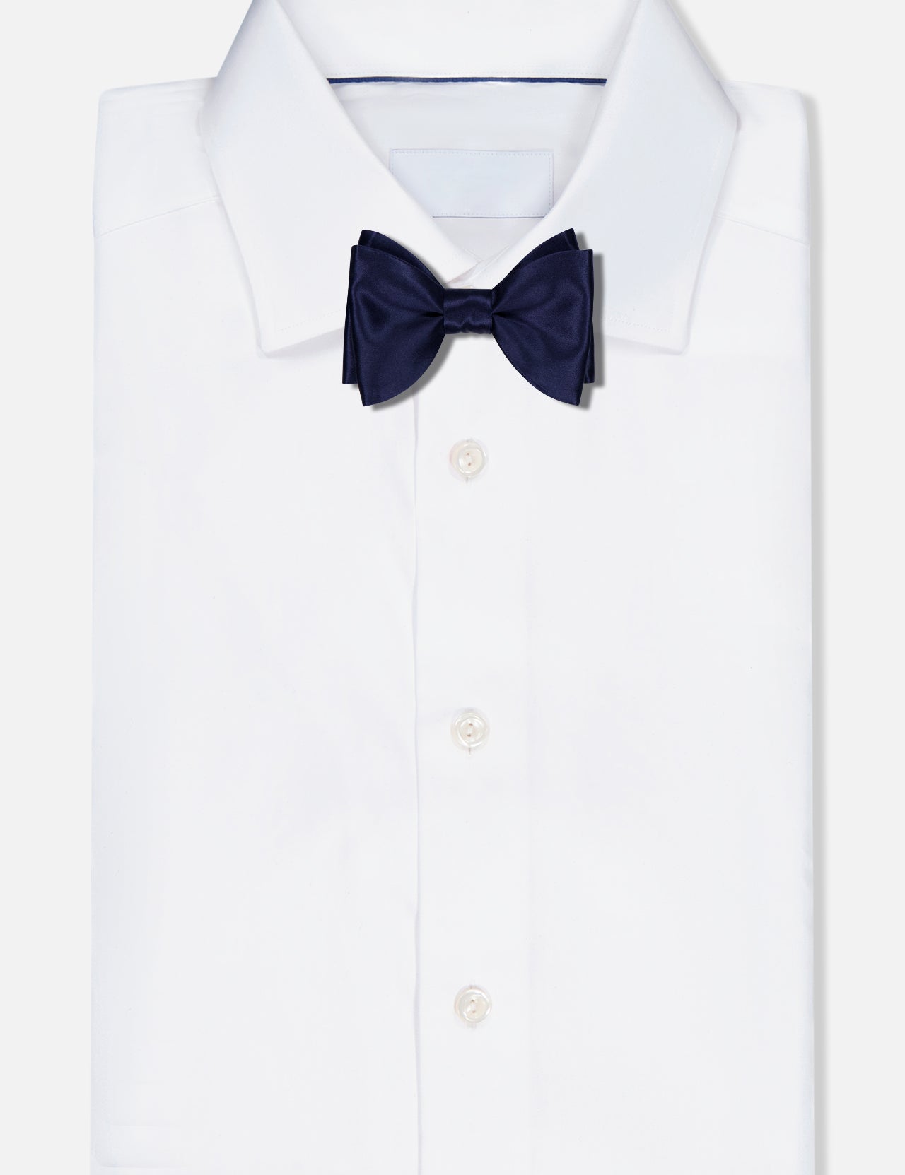 A neatly folded white dress shirt with a classic collar is paired with the ITALO FERRETTI Satin Bowtie, handmade in Italy from 100% silk and shown against a plain white background.