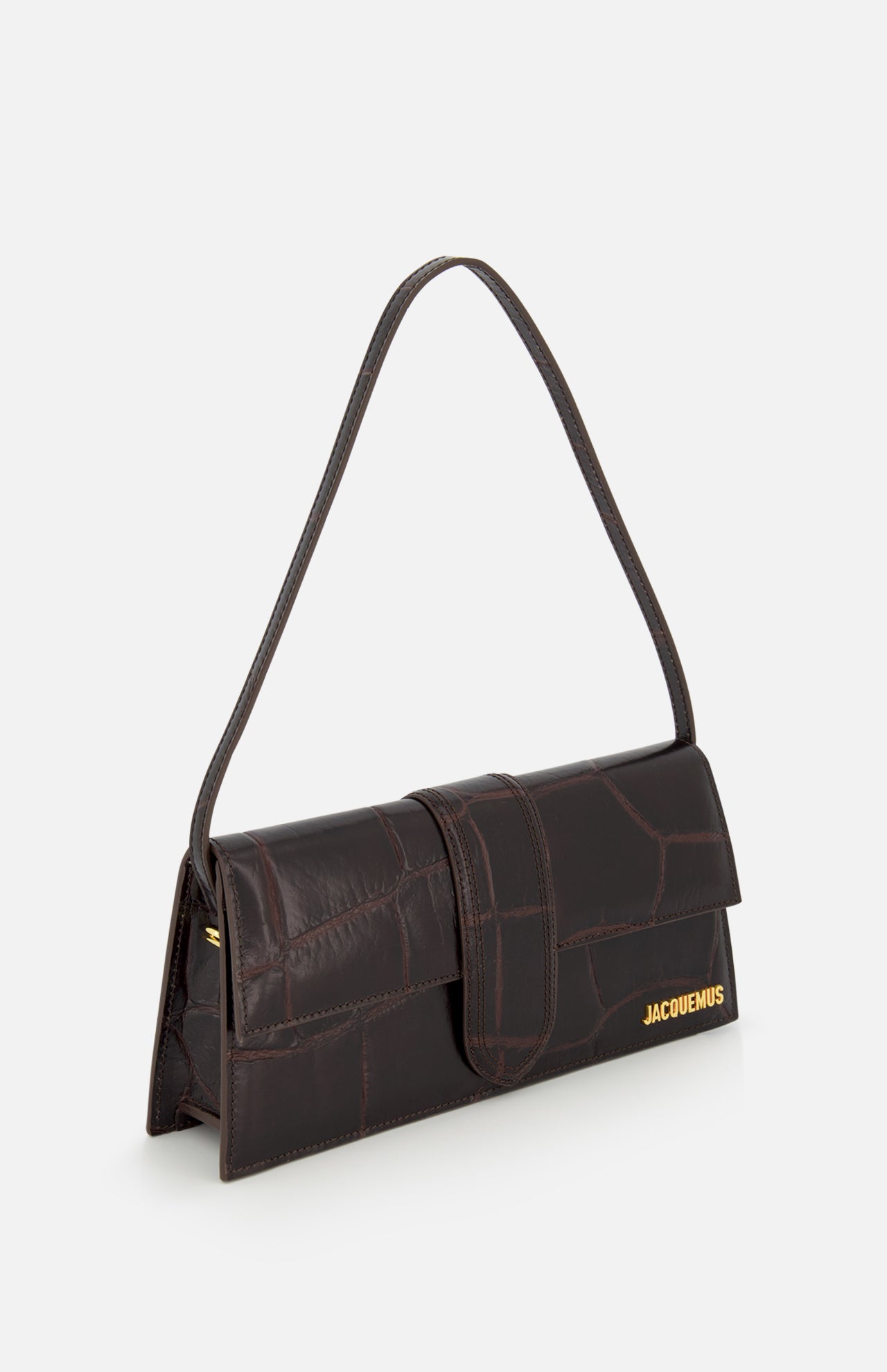 The JACQUEMUS Le Bambino Long Croco-effect Shoulder Bag features dark brown leather, a rectangular shape, flap closure, single shoulder strap, and gold logo at the bottom right corner, shown against a plain white background.