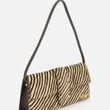 The JACQUEMUS Le Bambino Long Zebra Shoulder Bag is a rectangular shoulder bag made in Italy, crafted from luxurious calf hair with a zebra print pattern. It features a dark shoulder strap and is adorned with a gold Jacquemus logo on the lower right front corner, shown against a plain white background.